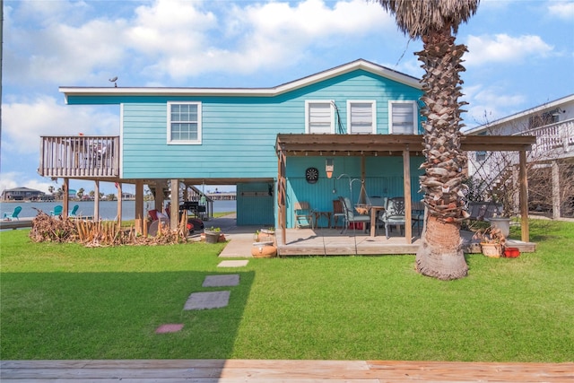 rear view of property with a carport, a deck with water view, a patio area, and a yard