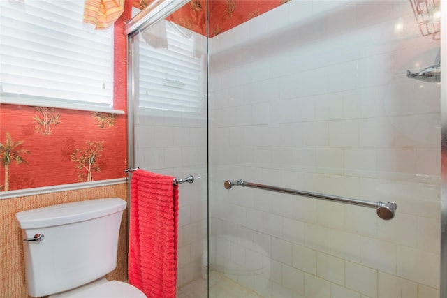 full bathroom with a wainscoted wall, a tile shower, toilet, and wallpapered walls