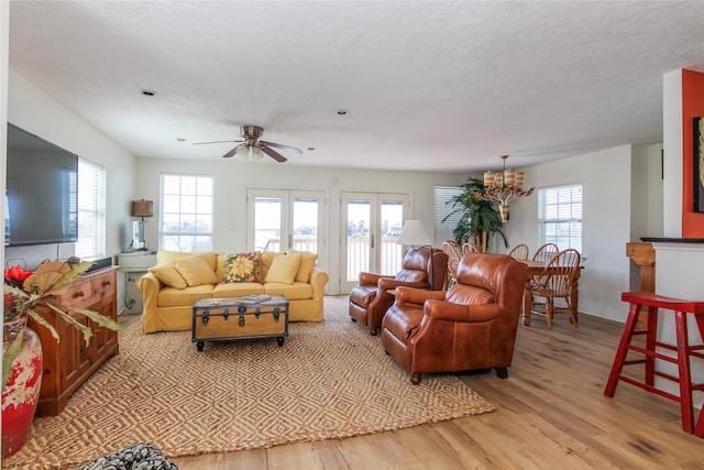 living area with light wood-type flooring, french doors, a healthy amount of sunlight, and a textured ceiling