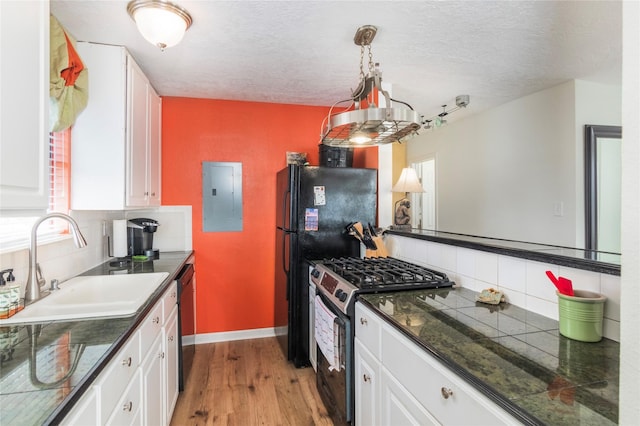 kitchen featuring electric panel, white cabinetry, a sink, and black appliances