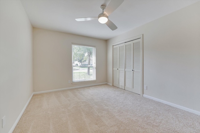 unfurnished bedroom with ceiling fan, light colored carpet, and a closet