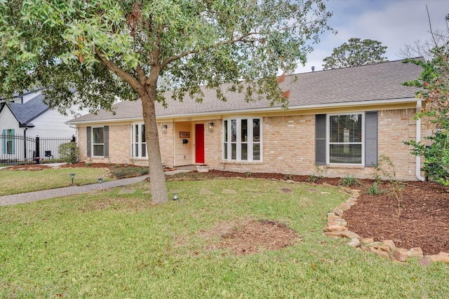 ranch-style home featuring a front lawn, fence, brick siding, and a shingled roof