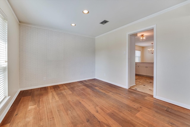 empty room with crown molding, light hardwood / wood-style floors, and a notable chandelier