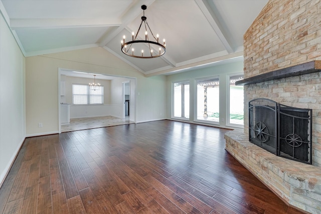 unfurnished living room featuring lofted ceiling with beams, dark hardwood / wood-style flooring, a brick fireplace, and a chandelier