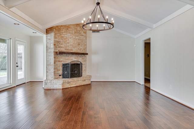 unfurnished living room with hardwood / wood-style flooring, an inviting chandelier, a fireplace, and lofted ceiling with beams