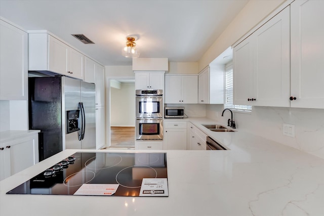 kitchen with appliances with stainless steel finishes, sink, and white cabinets