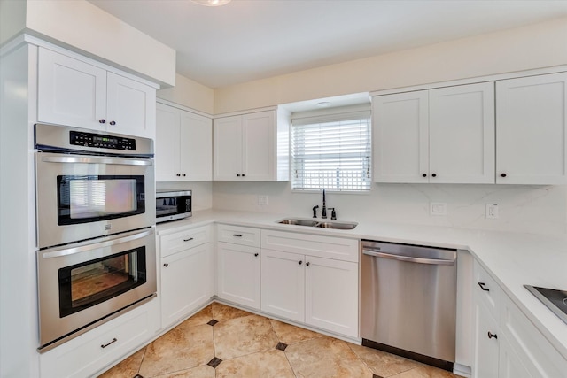 kitchen with stainless steel appliances, white cabinetry, sink, and light tile patterned floors