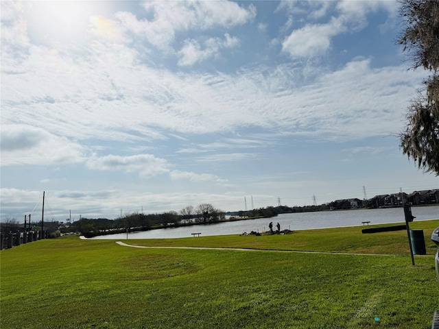 surrounding community with a water view and a lawn