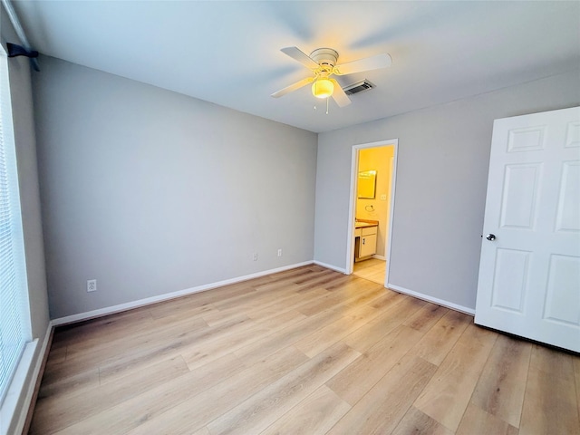unfurnished bedroom featuring ceiling fan, light wood-style floors, baseboards, ensuite bathroom, and visible vents