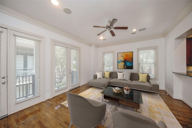 living area with plenty of natural light, wood finished floors, visible vents, and crown molding