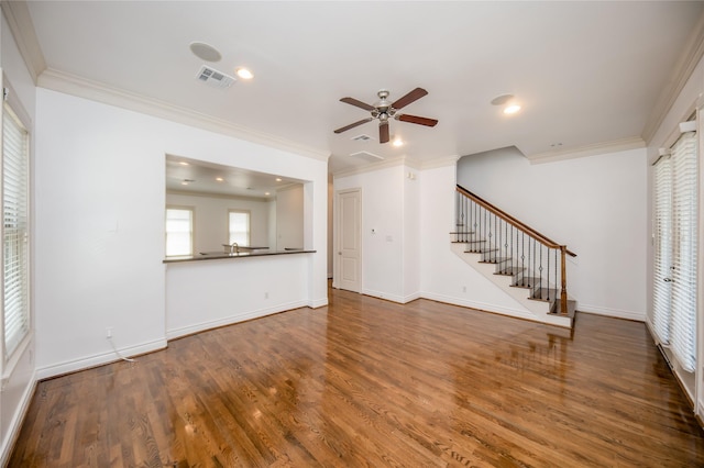 unfurnished living room featuring visible vents, baseboards, stairway, dark wood-style flooring, and crown molding