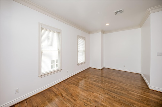 spare room with visible vents, crown molding, baseboards, and wood finished floors