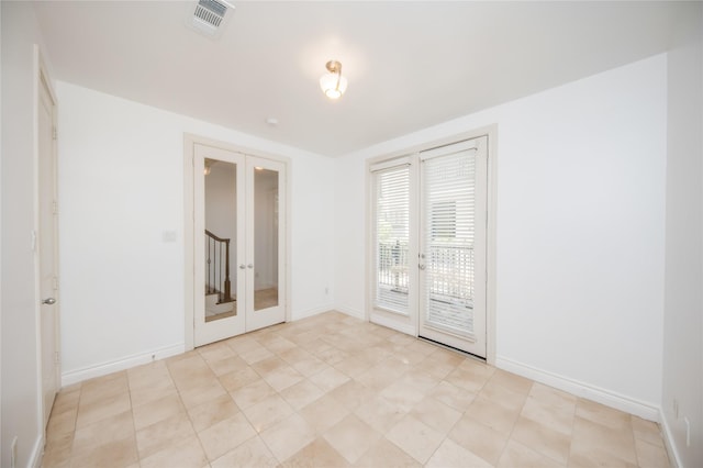 empty room with french doors, visible vents, and baseboards