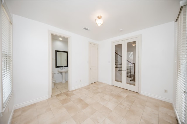 spare room featuring french doors, visible vents, and baseboards