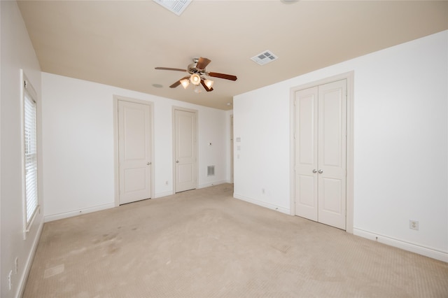 unfurnished bedroom with light carpet, two closets, and visible vents