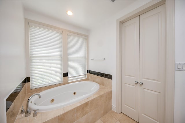 bathroom with a jetted tub, tile patterned flooring, and a closet