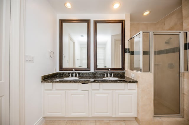 bathroom featuring double vanity, a shower stall, a sink, and recessed lighting