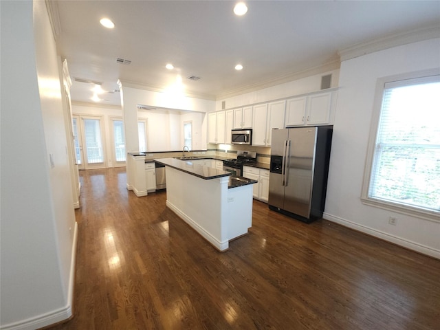 kitchen featuring stainless steel appliances, dark countertops, white cabinetry, and a sink