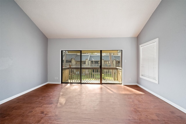 unfurnished room with lofted ceiling, hardwood / wood-style floors, and a textured ceiling