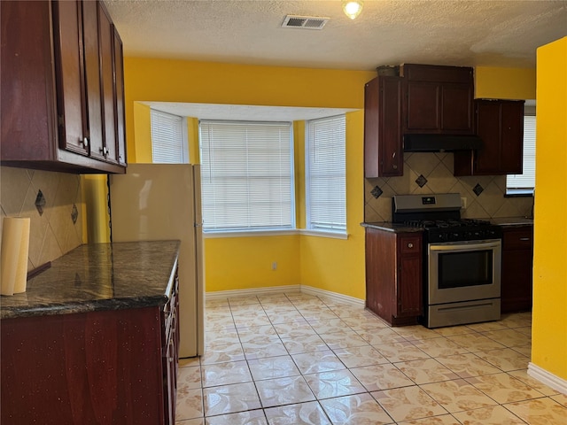 kitchen featuring light tile patterned floors, white refrigerator, tasteful backsplash, gas stove, and a textured ceiling