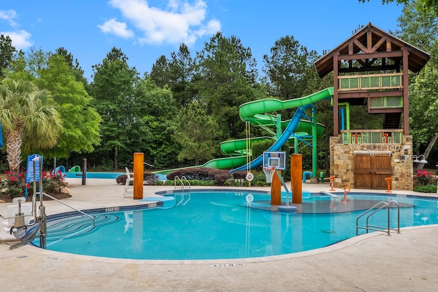 pool with a patio, a water slide, and exterior fireplace