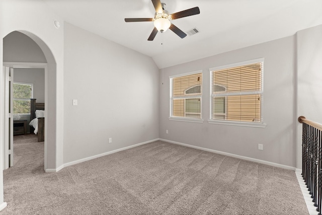 empty room with lofted ceiling, carpet, visible vents, and baseboards