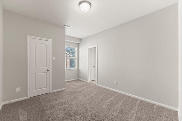 carpeted spare room featuring visible vents and baseboards