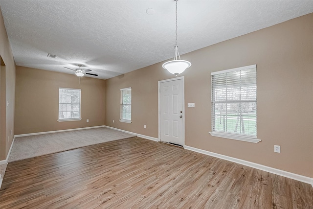 foyer featuring ceiling fan, visible vents, a textured ceiling, and wood finished floors