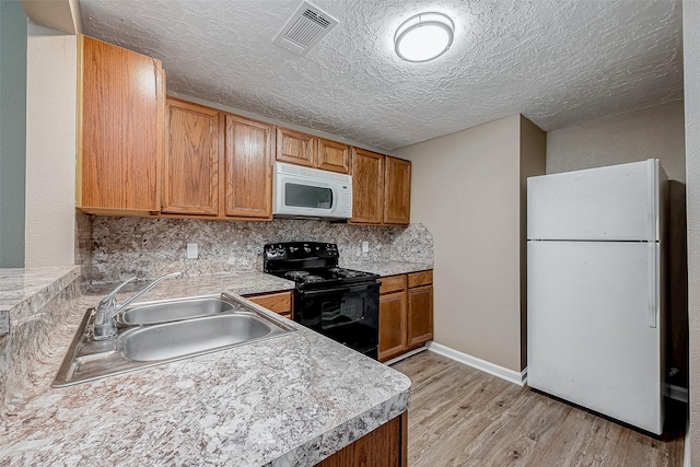 kitchen featuring white appliances, visible vents, a sink, light wood-style floors, and backsplash