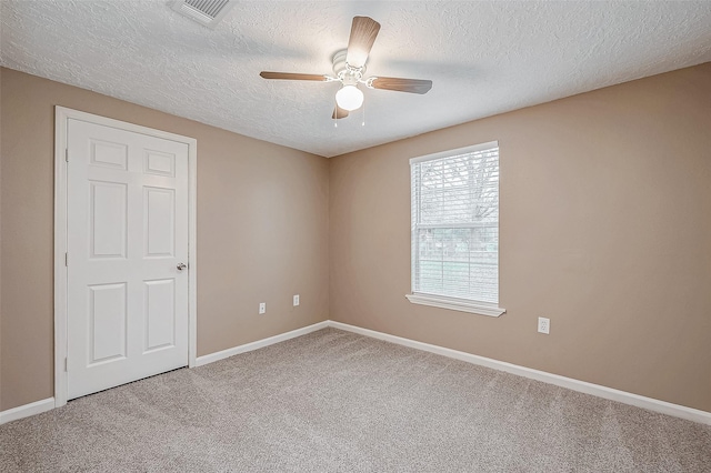 carpeted spare room featuring visible vents, a textured ceiling, baseboards, and ceiling fan