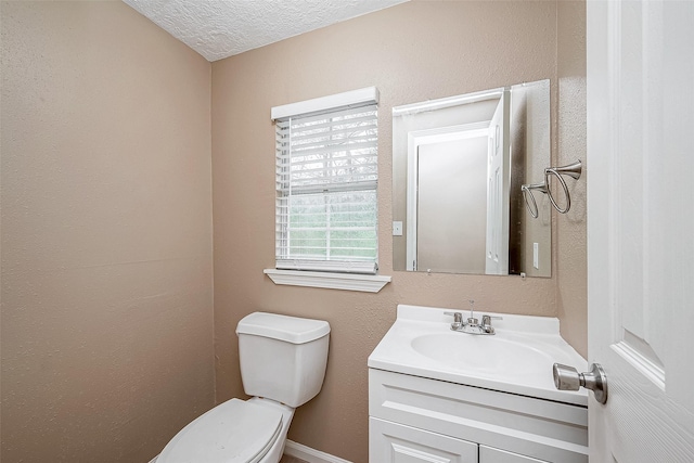 half bathroom with vanity, toilet, a textured wall, and a textured ceiling