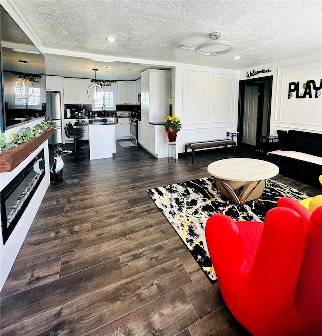 living area with a textured ceiling and dark wood-type flooring