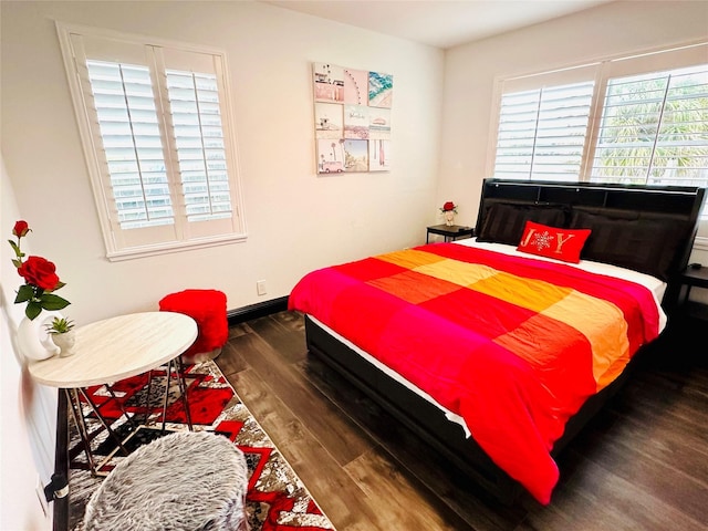 bedroom with multiple windows, baseboards, and wood finished floors