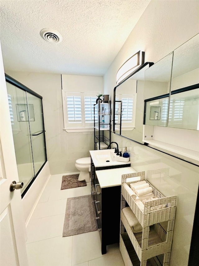 full bath with a shower with shower door, visible vents, a textured ceiling, and tile patterned floors