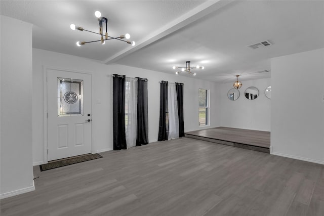 foyer entrance featuring an inviting chandelier, beam ceiling, and light hardwood / wood-style flooring