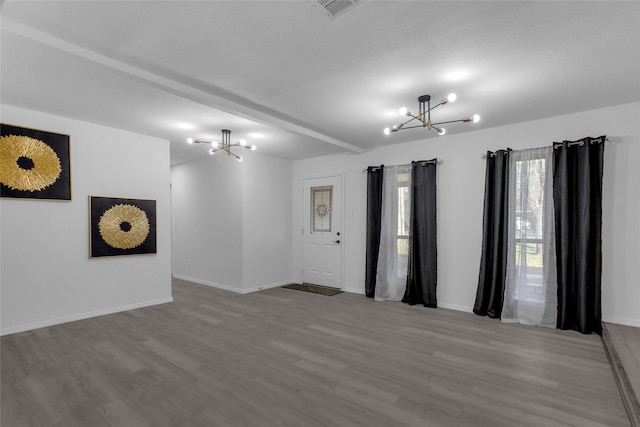 spare room with beamed ceiling, hardwood / wood-style floors, a textured ceiling, and an inviting chandelier