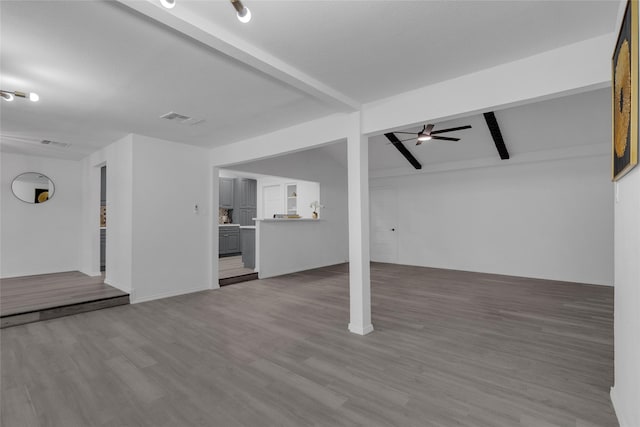 unfurnished living room with beam ceiling, wood-type flooring, and ceiling fan