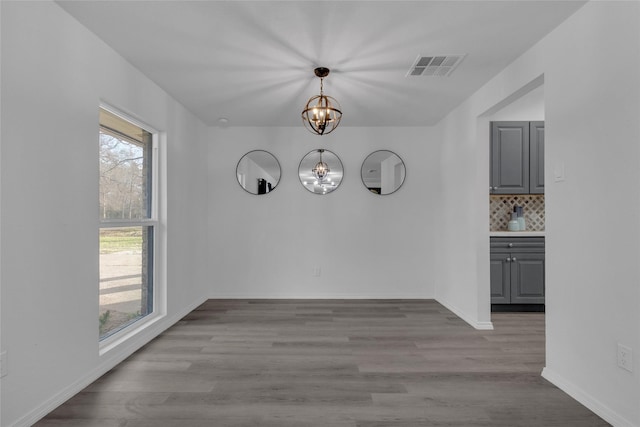 unfurnished dining area with an inviting chandelier and light hardwood / wood-style floors