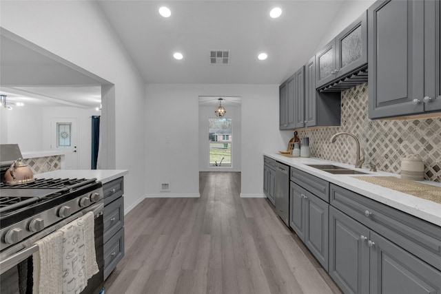 kitchen featuring gray cabinets, appliances with stainless steel finishes, decorative light fixtures, sink, and light hardwood / wood-style flooring