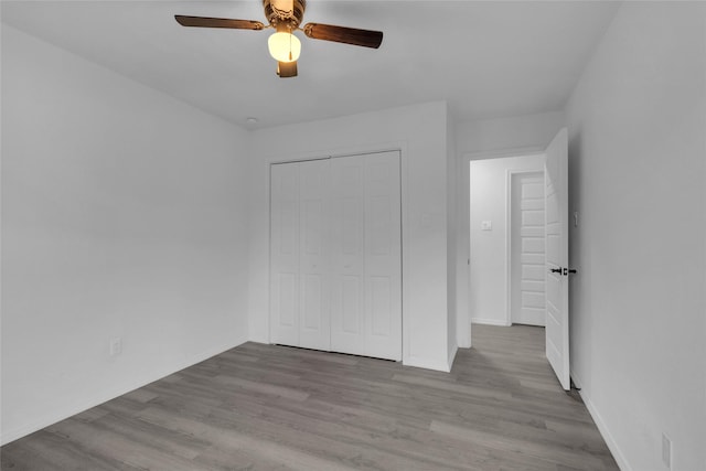 unfurnished bedroom with ceiling fan, light hardwood / wood-style floors, and a closet