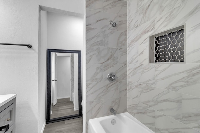 bathroom featuring vanity, wood-type flooring, and tiled shower / bath