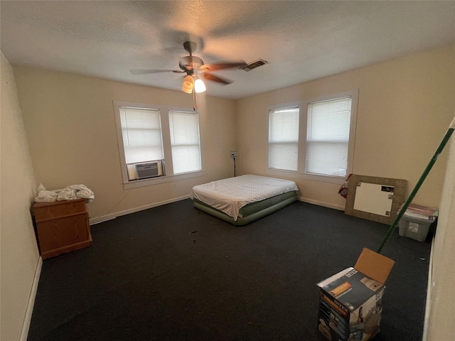 unfurnished bedroom featuring multiple windows, cooling unit, ceiling fan, and dark colored carpet