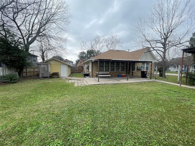 back of property featuring a patio, a yard, and a storage unit