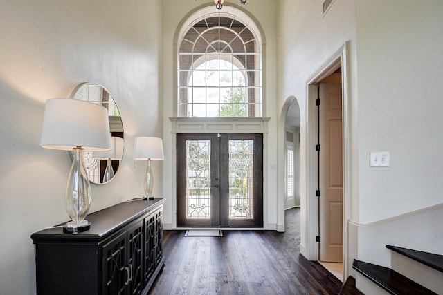 foyer with a towering ceiling, dark hardwood / wood-style floors, and french doors