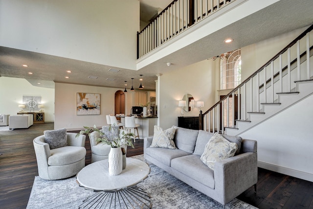 living room with dark hardwood / wood-style floors, ornate columns, and a high ceiling