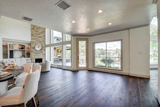 unfurnished living room featuring ornamental molding, dark hardwood / wood-style floors, a textured ceiling, and a fireplace