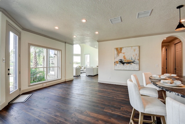 dining room with dark hardwood / wood-style flooring, crown molding, and a textured ceiling