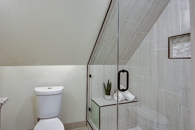 bathroom with a shower with door, lofted ceiling, and toilet