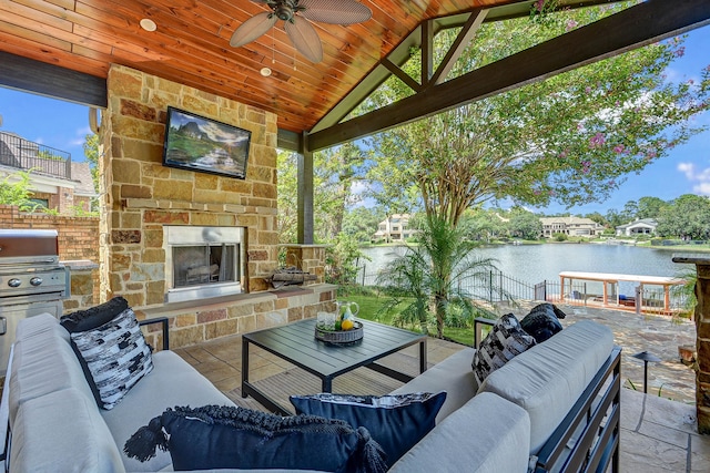 view of patio with a water view, ceiling fan, an outdoor living space with a fireplace, and a gazebo