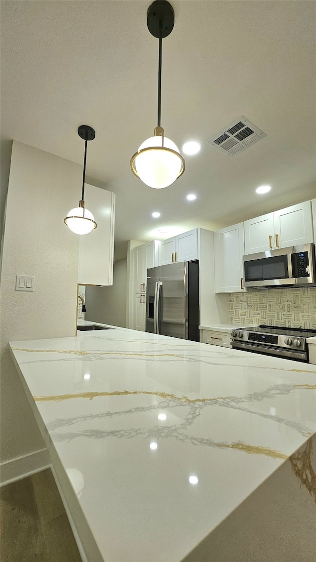 kitchen with sink, white cabinetry, decorative light fixtures, appliances with stainless steel finishes, and decorative backsplash